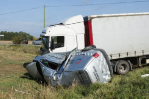Truck Accidents Legal Funding | 1,600+ Clients Served | Up to $1 Million The aftermath of a serious truck accident, showing a damaged semi-truck and overturned delivery van in grass on the side of a road.