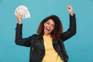 cheerful woman in leather jacket holding money