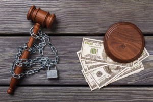 A gavel wrapped in a chain separated from some money.